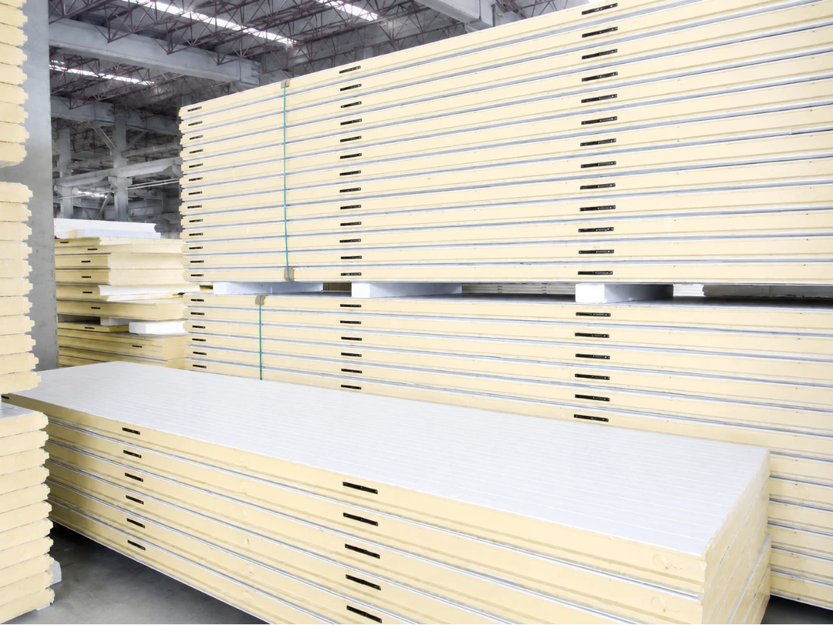 Polyurethane cold storage panels with tongue-and-groove edges and built-in cam locks, stacked in the factory