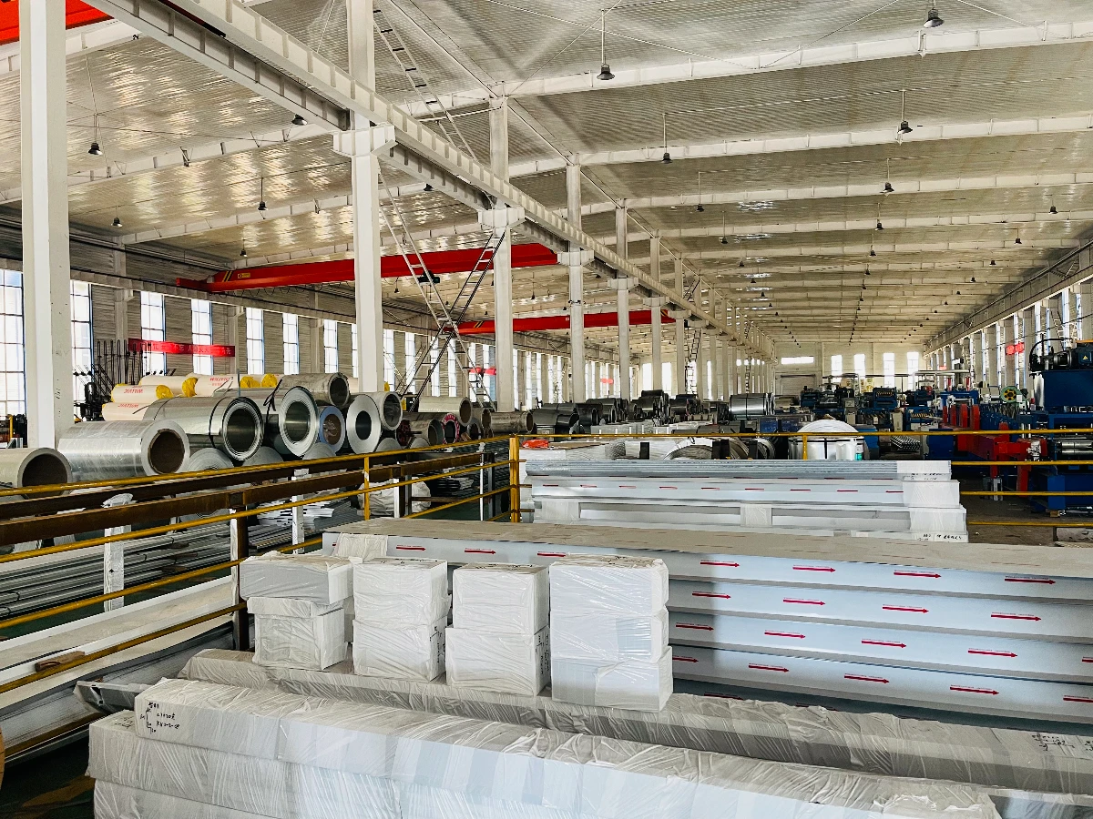 VIKKINS production hall showing steel coil, roll-forming lines and finished panels wrapped and labeled for export