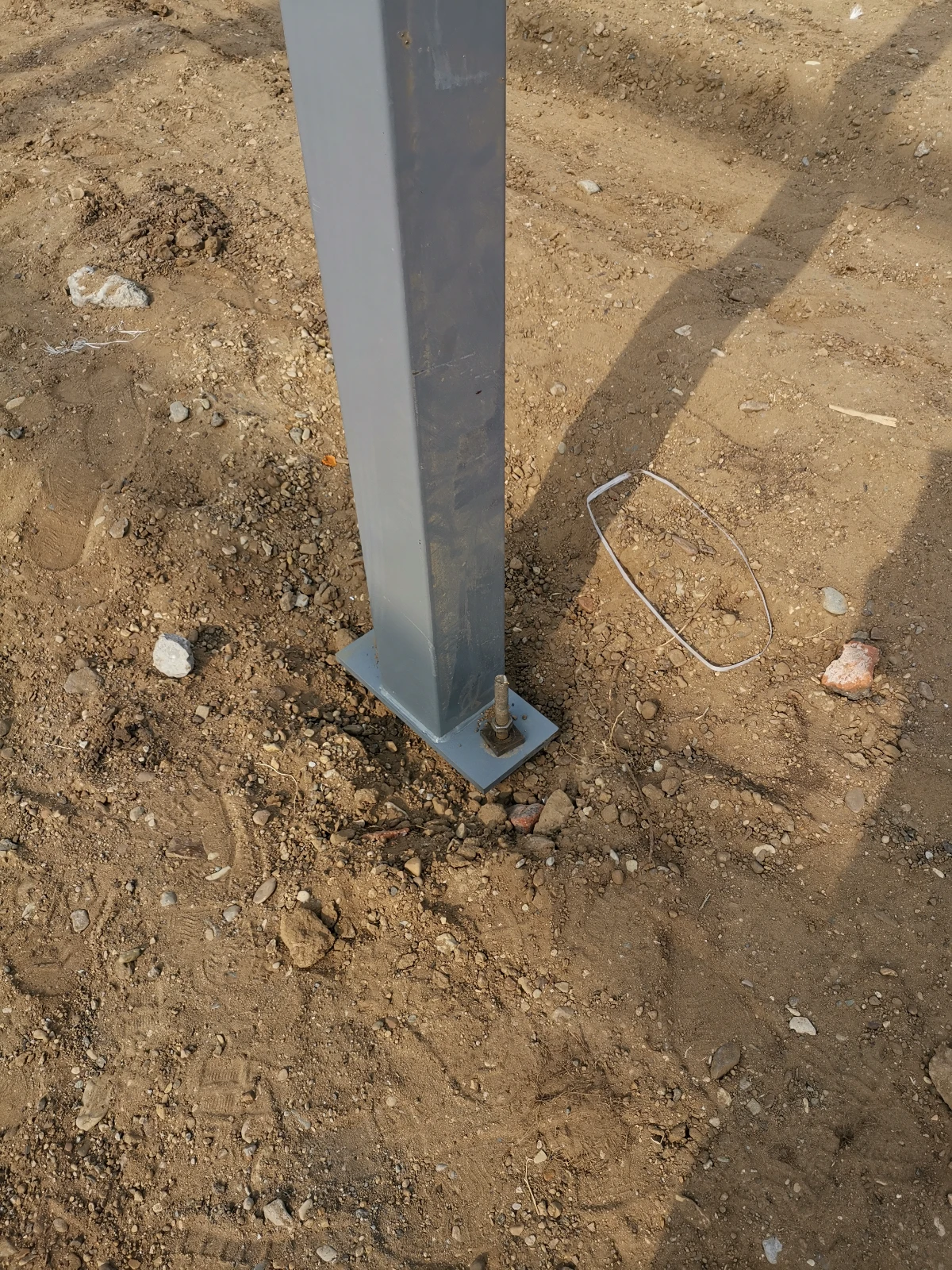 Erected steel column standing on its base plate and anchor bolt on a prepared site foundation