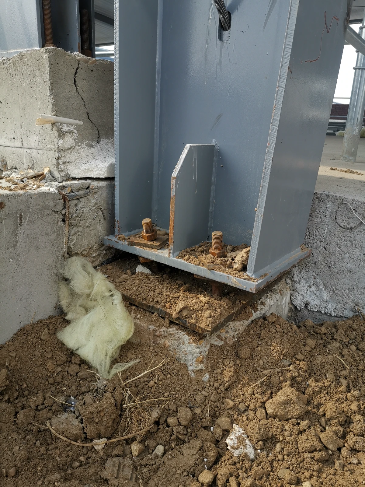 Steel column base plate bolted to anchor bolts on a concrete foundation with stiffener plate