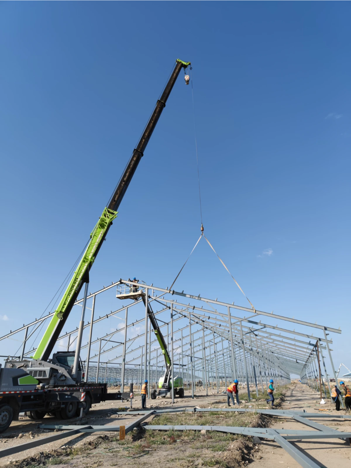 Crane lifting a portal-frame steel structure during dairy barn installation