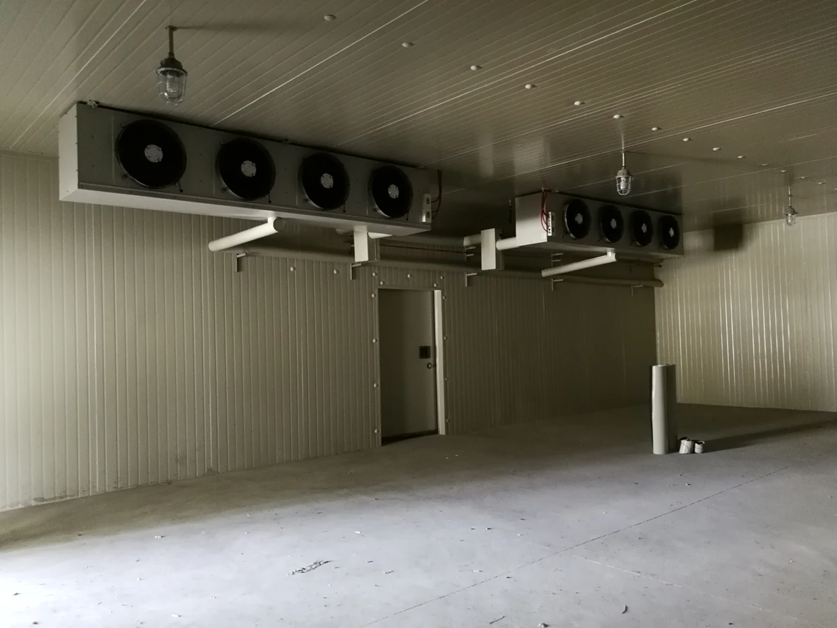 Interior de una cámara frigorífica con enfriadores de unidad montados en el techo y puerta aislada de cámara frigorífica