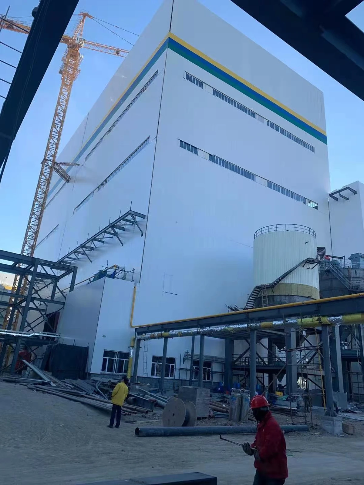 Tall boiler house steel structure clad on a Vikkins power plant project, with pipe racks at its base
